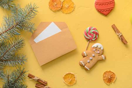 Envelope with card, fir branches, cookies and dried orange slices on color background