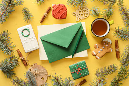 Composition with envelope, cup of tea, cookies and fir branches on color backgroundの写真素材