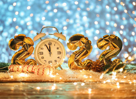 Stylish Christmas clock, decor, snow and figure 2022 made of balloons on table against blurred backgroundの写真素材