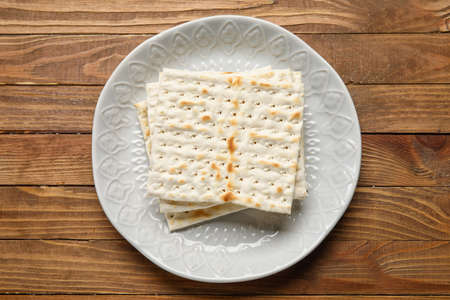 Plate with Jewish flatbread for Passover on wooden background