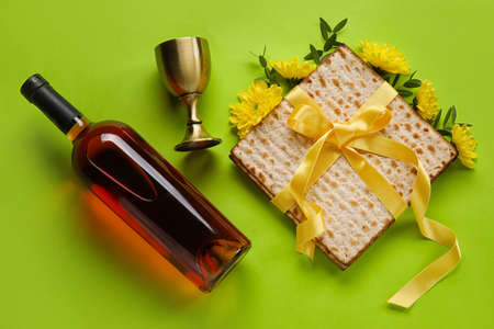 Jewish flatbread with goblet and bottle of wine on color background
