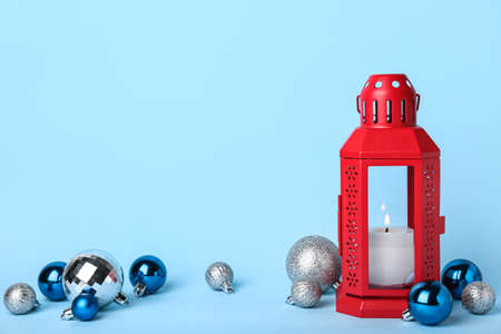 Christmas lantern with burning candle and balls on blue background