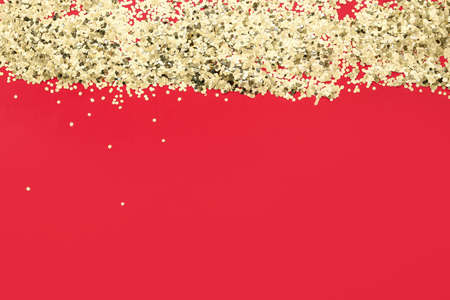 Heap of golden confetti on red background