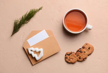 Envelope with cup of tea and cookies on color backgroundの写真素材