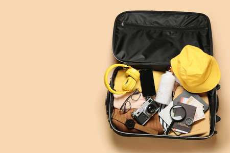 Suitcase with packed travel accessories on color backgroundの写真素材