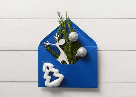 Envelope with Christmas decorations on white wooden background