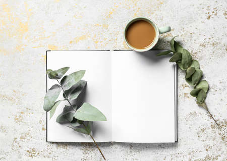 Cup of tasty coffee, book and eucalyptus branches on light backgroundの写真素材