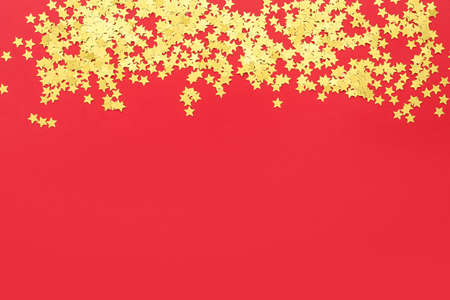Heap of golden confetti on red backgroundの写真素材
