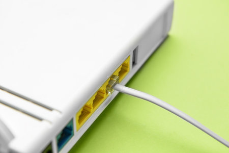 Modern wi-fi router and internet cable on green background, closeupの写真素材