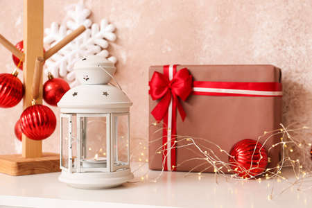 Christmas gift, lantern and decor on table near color wallの写真素材