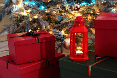 Lantern and gifts near Christmas tree in roomの写真素材