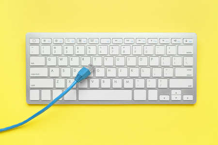 Internet cable and computer keyboard on yellow backgroundの写真素材