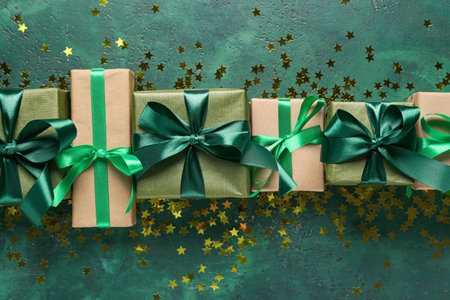 Different Christmas gifts and golden confetti on color background, closeup