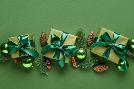 Christmas gifts, fir branches, cones and decorations on green backgroundの写真素材
