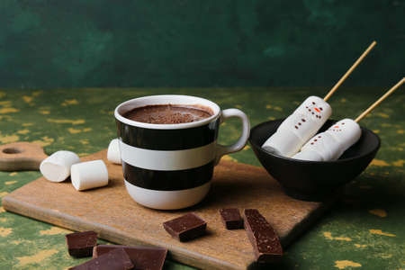 Cup of natural hot chocolate with marshmallows on green background
