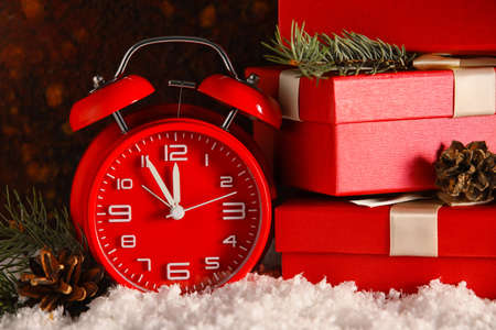 Alarm clock and stack of Christmas gifts on snow against grunge backgroundの写真素材