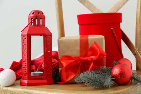 Chair with Christmas gifts, lantern and decor on light background
