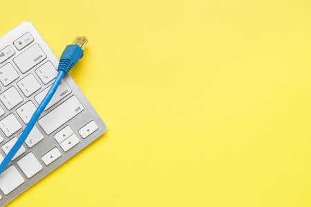 Internet cable and computer keyboard on yellow backgroundの写真素材