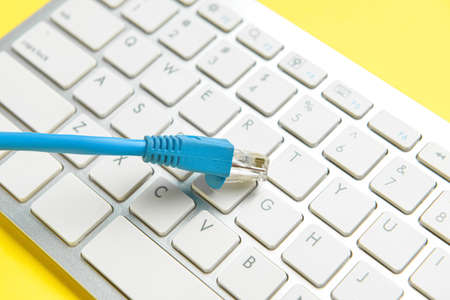 Internet cable and computer keyboard on yellow background, closeupの写真素材