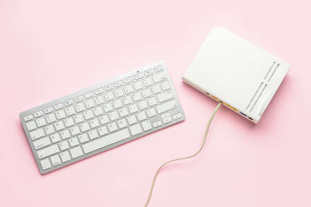 Wifi router with internet cable and computer keyboard on pink backgroundの写真素材
