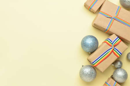 Gift boxes with rainbow LGBT ribbons and Christmas balls on beige backgroundの写真素材