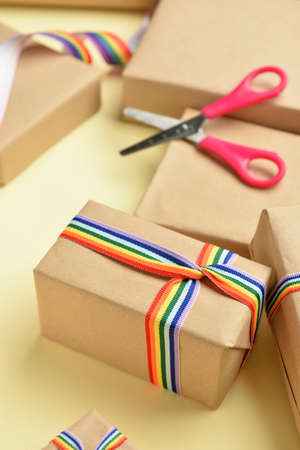 Gift boxes with rainbow LGBT ribbons, paper and scissors on beige background, closeupの写真素材