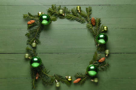 Frame made of fir branches, Christmas decorations and cones on color wooden backgroundの写真素材