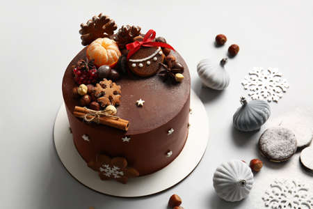 Stand with tasty Christmas chocolate cake and decor on light backgroundの写真素材