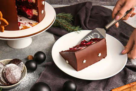Woman with piece of tasty Christmas chocolate cake on gray backgroundの写真素材