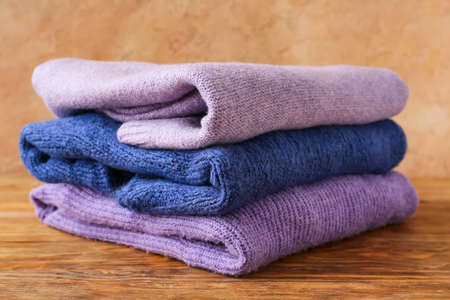 Stack of different cozy sweaters on wooden table