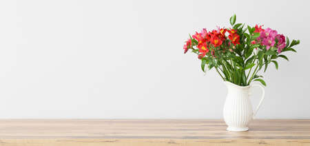 Vase with bouquet of beautiful alstroemeria flowers on table near light wall. Banner designの写真素材