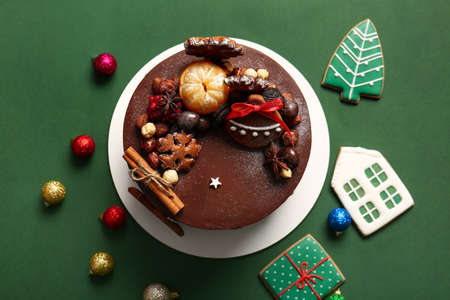 Stand with tasty Christmas chocolate cake and balls on green backgroundの写真素材