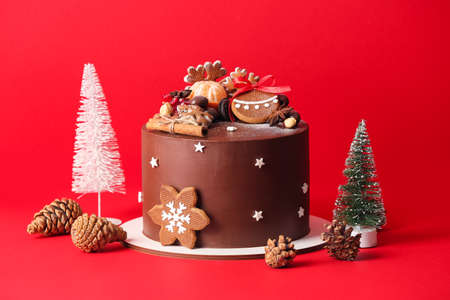 Stand with tasty Christmas chocolate cake on red backgroundの写真素材
