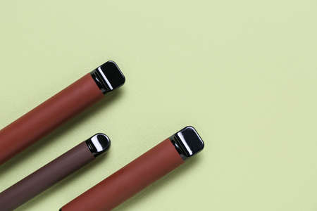 Disposable electronic cigarettes on green background, closeup