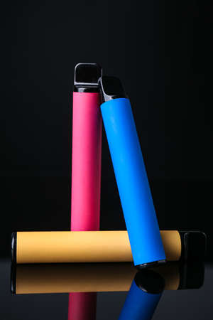 Different disposable electronic cigarettes on dark background