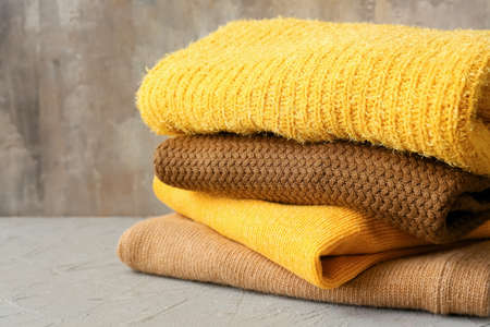 Stack of different cozy sweaters on grunge backgroundの写真素材