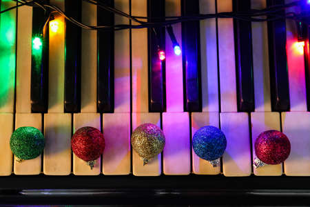 Christmas balls with glowing lights on piano keys, closeupの写真素材