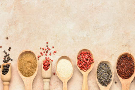Spoons with aromatic spices on beige background
