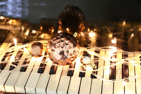 Christmas balls and glowing lights on piano keys, closeupの写真素材