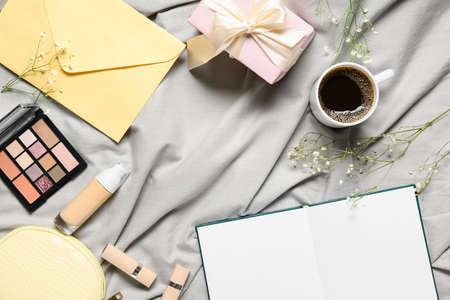 Frame made of opened book, cup of coffee, envelope and decorative cosmetics on bed