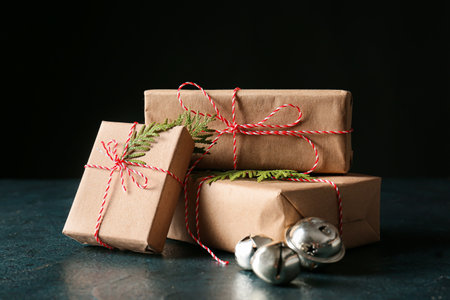 Stylish Christmas gift boxes on table against dark background