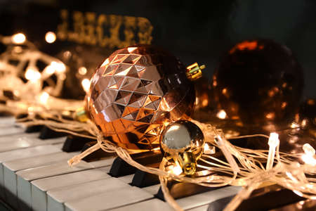 Christmas balls and glowing lights on piano keys, closeupの写真素材