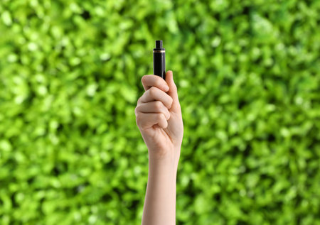 Female hand with disposable electronic cigarette outdoors, closeupの写真素材
