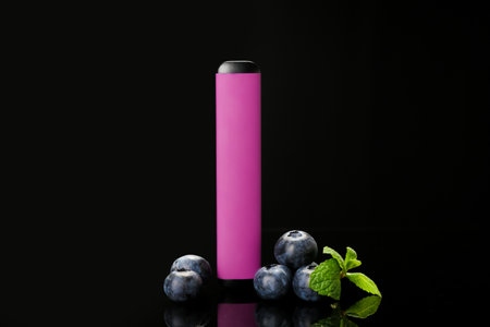 Disposable electronic cigarette and blueberries on dark background