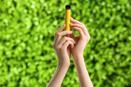 Female hands with disposable electronic cigarette outdoors, closeupの写真素材