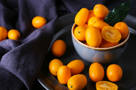 Bowl with tasty kumquat fruits on dark backgroundの写真素材