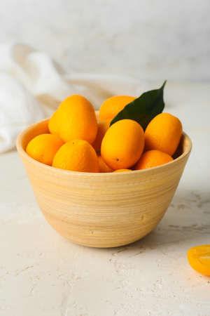 Bowl with tasty kumquat fruits on light backgroundの写真素材