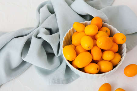 Bowl with tasty kumquat fruits on light backgroundの写真素材