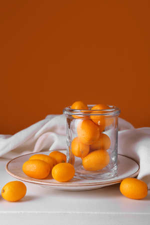 Jar with tasty kumquat fruits on light wooden tableの写真素材