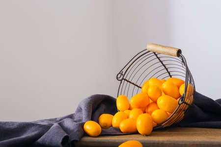 Basket with tasty kumquat fruits on wooden tableの写真素材